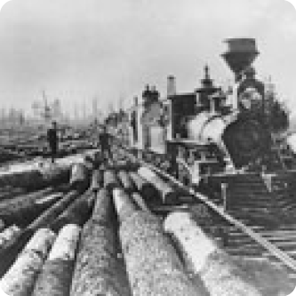 B/W photo of train with logs in foreground