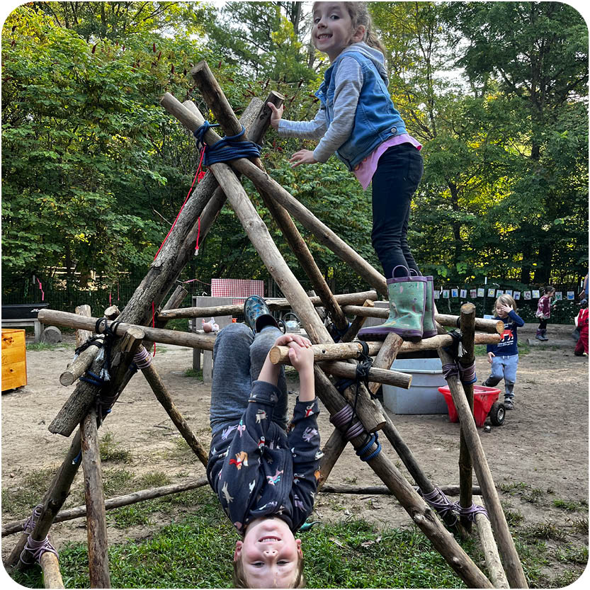 Kids playing in wooded play area and smiling 