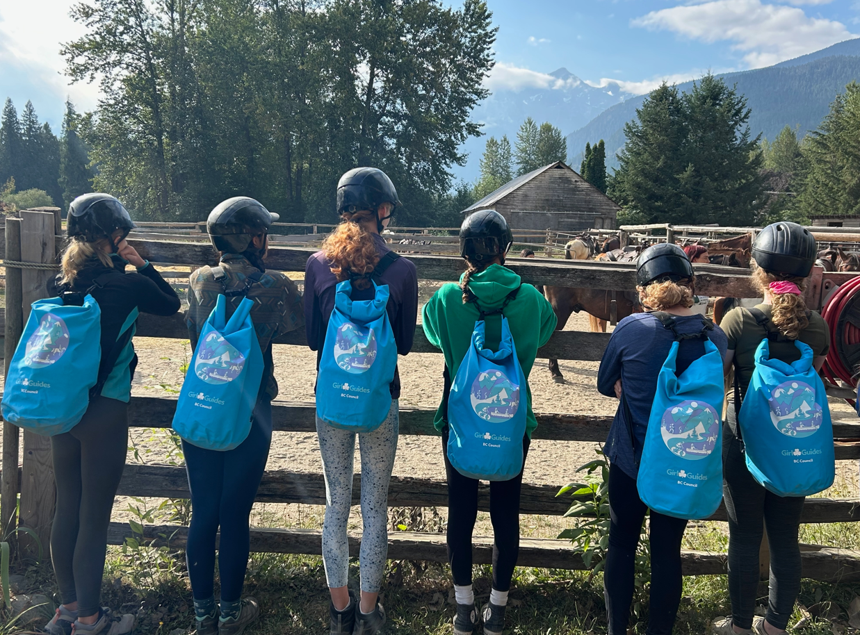 Image of the backs of older youth looking out over a horse pasture